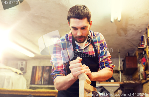 Image of carpenter working with plane and wood at workshop