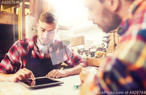 Image of workmen with tablet pc and blueprint at workshop