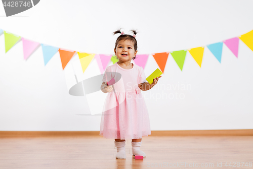 Image of happy baby girl with toy blocks at birthday party