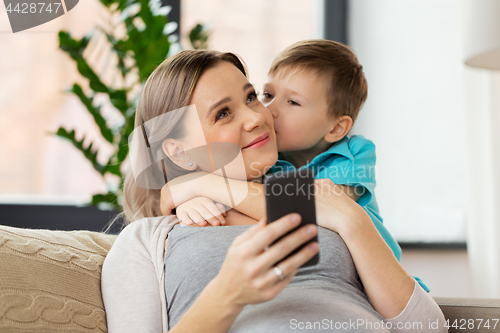 Image of son kissing happy pregnant mother at home