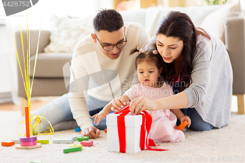 Image of baby girl with birthday gift and parents at home 