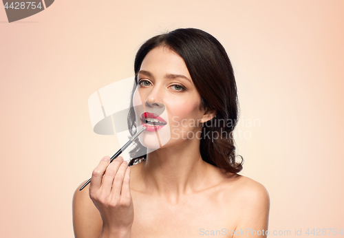 Image of beautiful woman with make up brush for lipstick