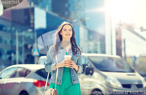 Image of happy young woman drinking coffee on city street