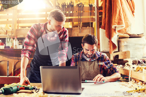 Image of carpenters with laptop and blueprint at workshop