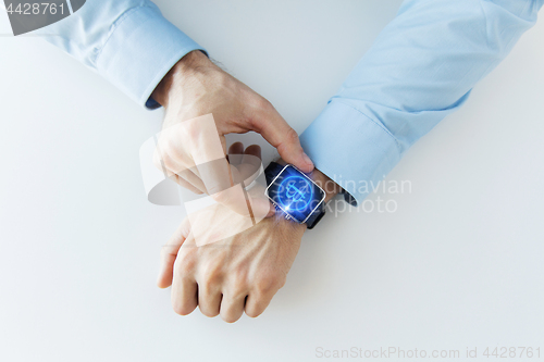 Image of close up of hands with bitcoin on smart watch