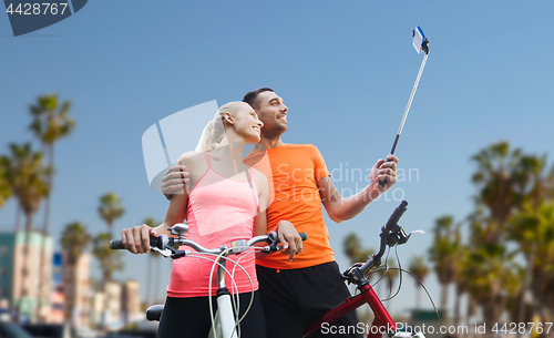 Image of couple with bicycle and smartphone selfie stick