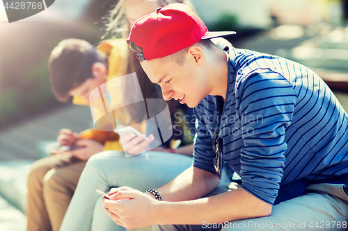 Image of happy teenage friends with smartphones outdoors