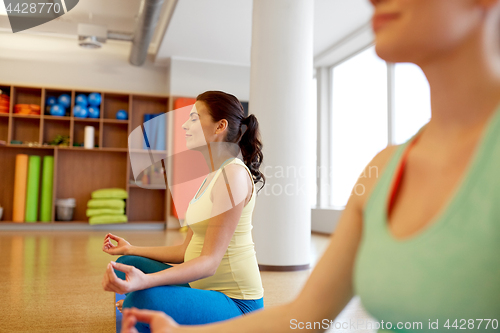 Image of happy pregnant women meditating at gym yoga