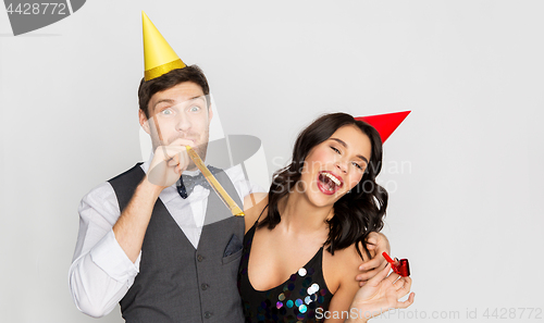 Image of happy couple with party blowers having fun