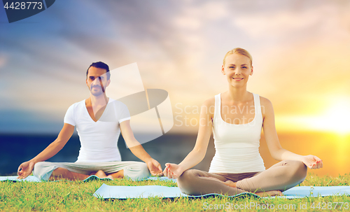 Image of happy couple making yoga and meditating outdoors