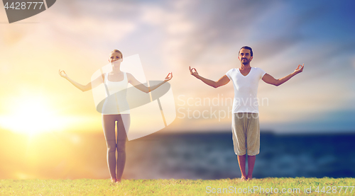 Image of couple making yoga exercises outdoors