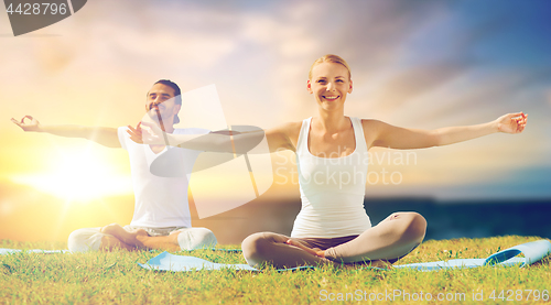 Image of happy couple making yoga and meditating outdoors