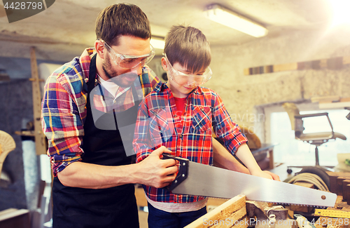 Image of father and son with saw working at workshop