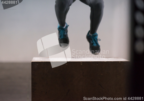 Image of black woman is performing box jumps at gym