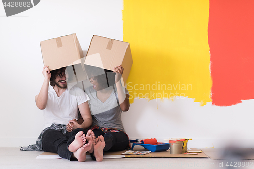 Image of young multiethnic couple playing with cardboard boxes