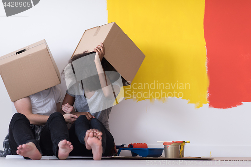 Image of young multiethnic couple playing with cardboard boxes