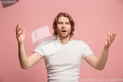 Image of The young attractive man looking suprised isolated on pink