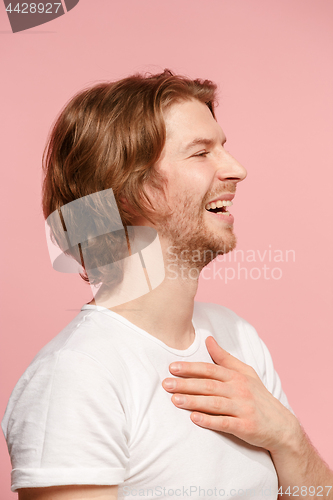 Image of The young attractive man looking suprised isolated on pink