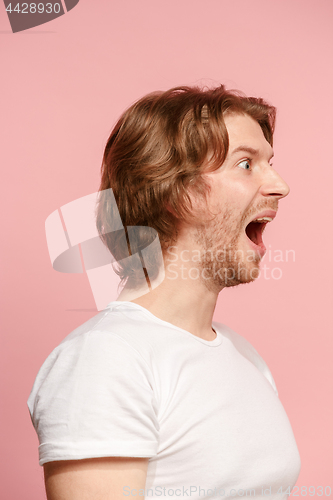 Image of The young attractive man looking suprised isolated on pink