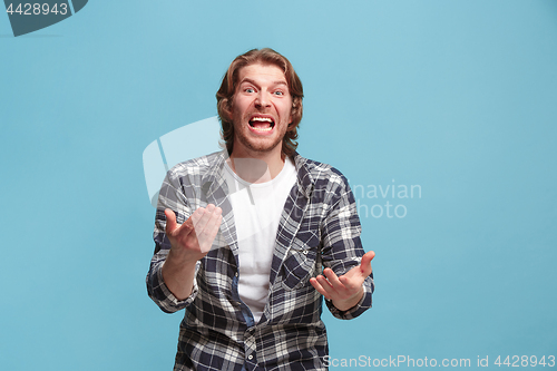 Image of Beautiful male half-length portrait isolated on blue studio backgroud. The young emotional surprised man