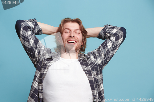 Image of The happy business man standing and smiling against blue background.