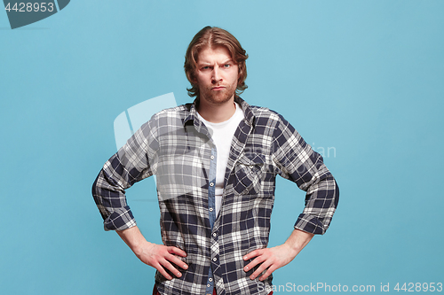 Image of The serious business man standing and looking at camera against bllue background.