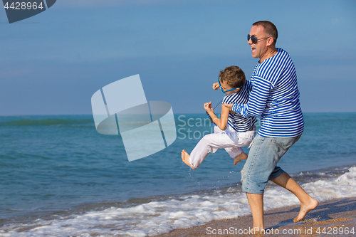 Image of Father and son playing on the beach at the day time. Concept of 