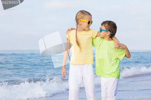 Image of Two happy children playing on the beach at the day time