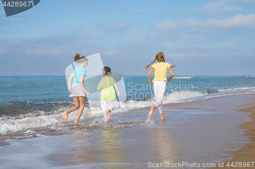 Image of Three happy children running on the beach at the day time.