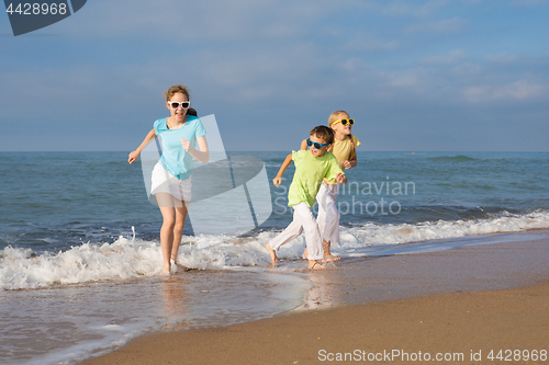 Image of Three happy children running on the beach at the day time.