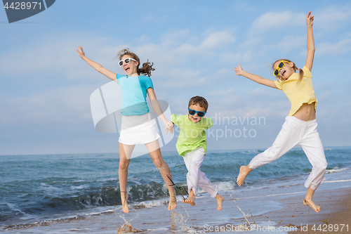 Image of Three happy children running on the beach at the day time.