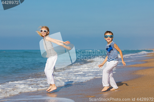 Image of Two happy children playing on the beach at the day time