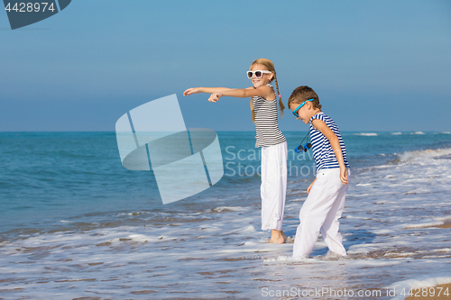 Image of Two happy children playing on the beach at the day time