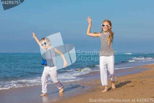 Image of Two happy children playing on the beach at the day time