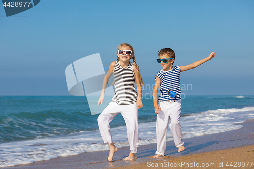 Image of Two happy children playing on the beach at the day time