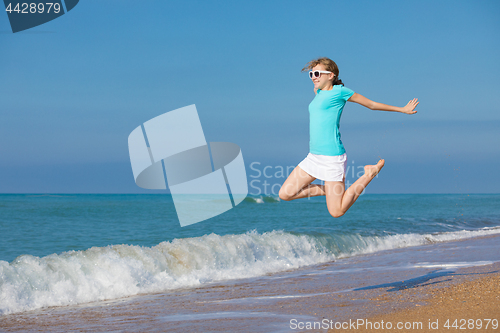 Image of teen girl jumping on the beach at blue sea shore in summer vacat