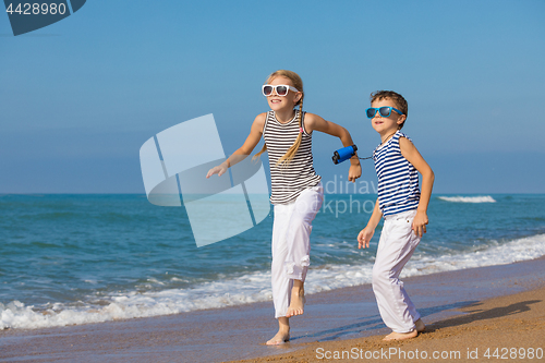 Image of Two happy children playing on the beach at the day time