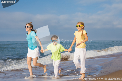 Image of Three happy children running on the beach at the day time.