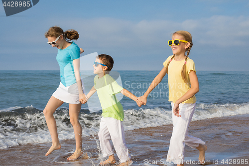 Image of Three happy children running on the beach at the day time.