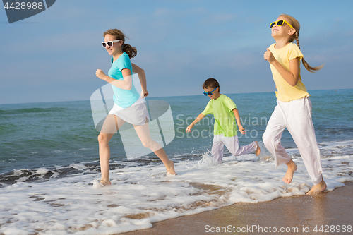 Image of Three happy children running on the beach at the day time.