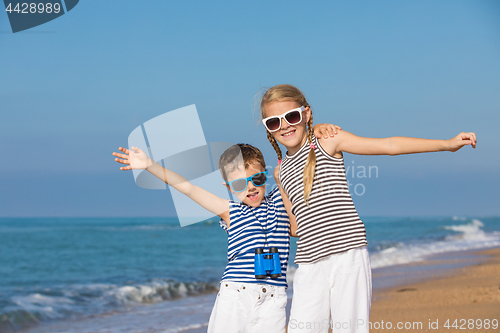 Image of Two happy children playing on the beach at the day time