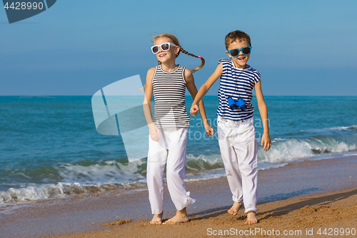 Image of Two happy children playing on the beach at the day time