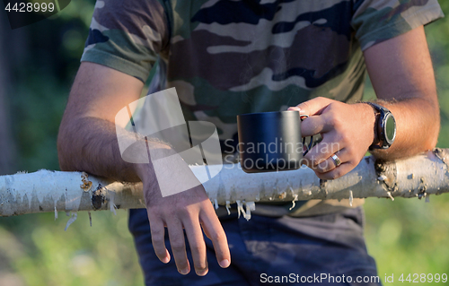 Image of Man drinking coffee on fenced ranch