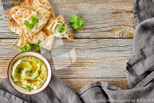 Image of bowl of hummus on wooden table