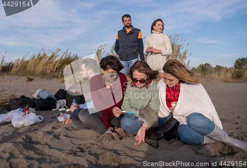 Image of Friends having fun at beach on autumn day