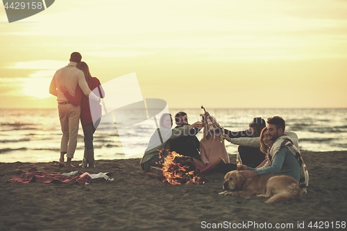 Image of Couple enjoying with friends at sunset on the beach