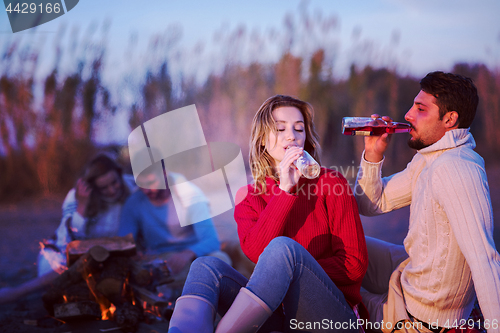 Image of Couple enjoying with friends at sunset on the beach