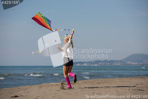 Image of Young Woman with kite at beach on autumn day