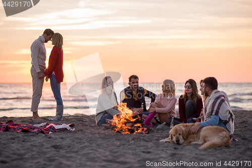 Image of Couple enjoying with friends at sunset on the beach