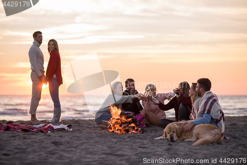 Image of Couple enjoying with friends at sunset on the beach